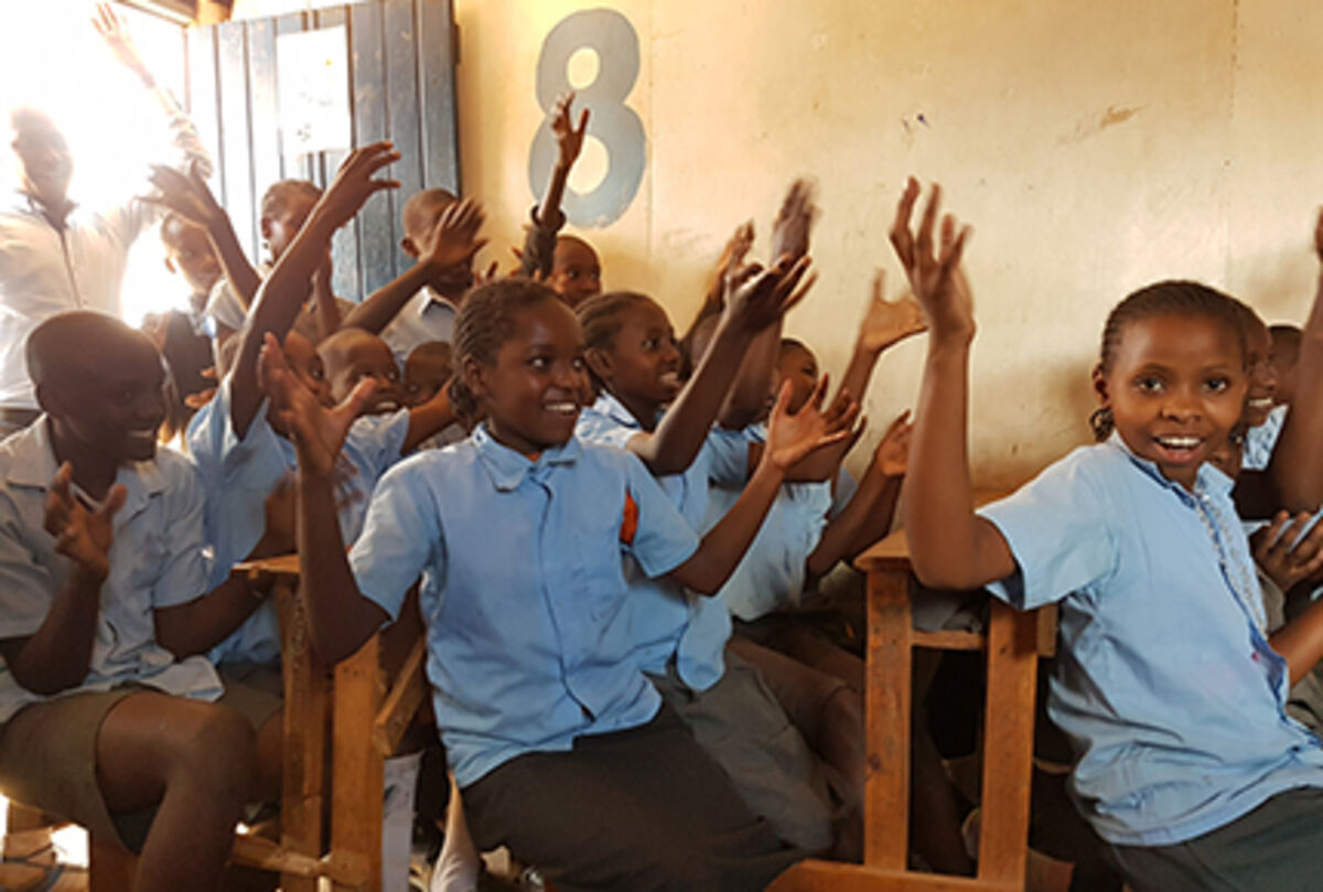 Classroom full with school children cheering in Kenya